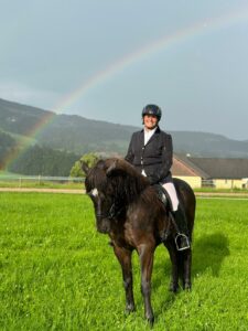 Helga Hochstöger sitzt auf Nòri unter einem Regenbogen